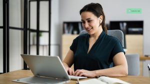 Smiling woman wearing earphones during a remote job interview, typing on a laptop, representing a positive and professional interview process.