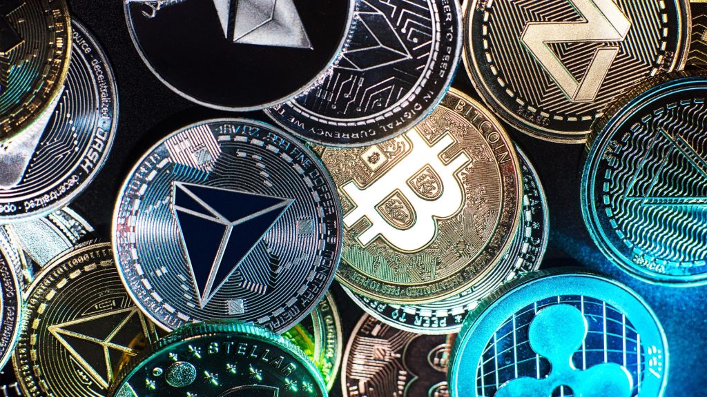Various cryptocurrency coins including Bitcoin, Ethereum, and Ripple, representing the growing need for crypto compliance in digital assets.
