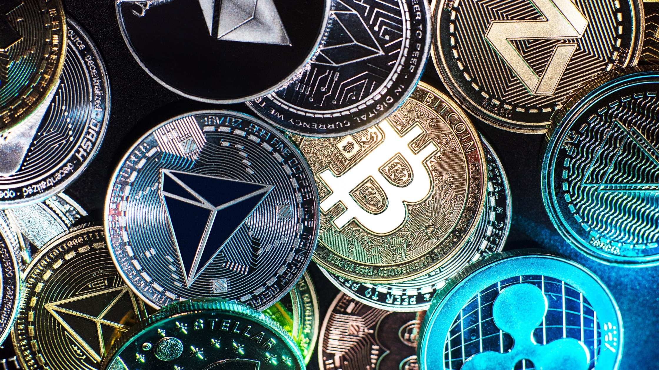 Various cryptocurrency coins including Bitcoin, Ethereum, and Ripple, representing the growing need for crypto compliance in digital assets.